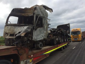 The burnt-out cab and trailer being recovered.